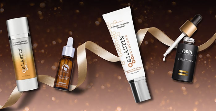 A collection of skincare products displayed against a brown background with a gold ribbon.